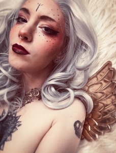 Angel cosplay boudoir portrait featuring a white-haired Angel with gold wings. NSFW prints from this photoshoot are available in the BlessedShadows Etsy shop